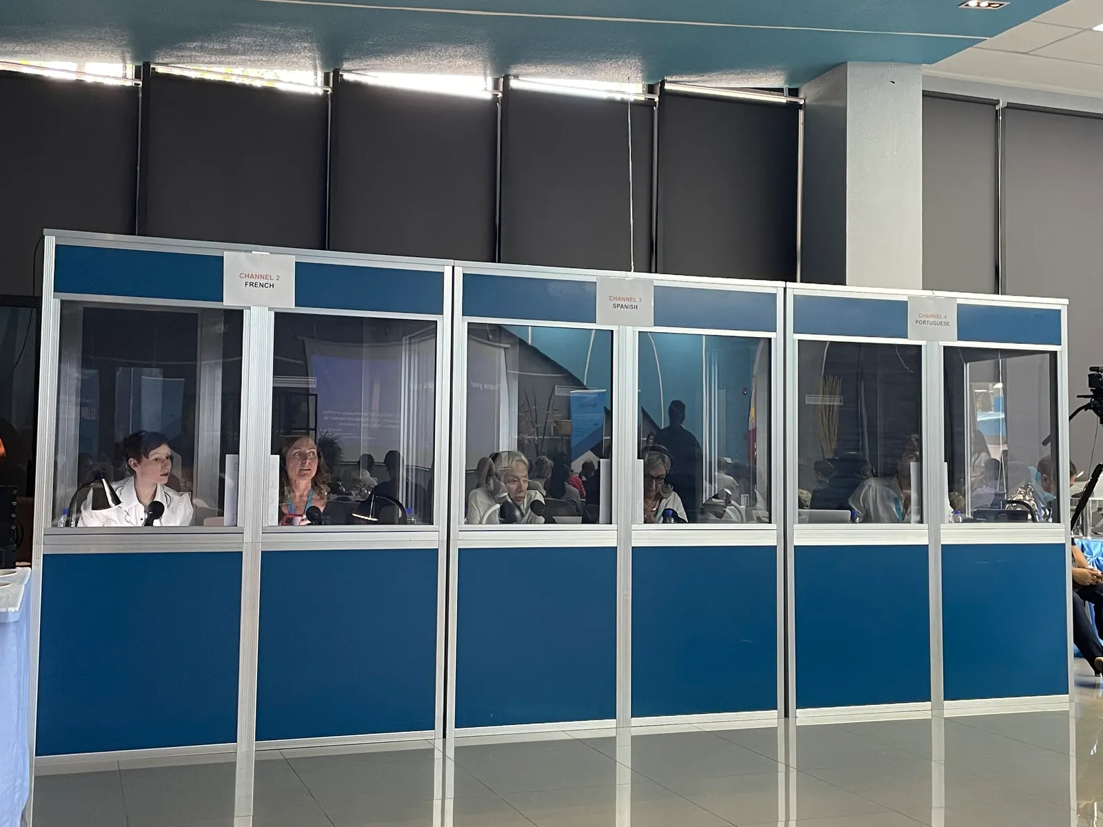 Simultaneous interpretation booths with interpreters working in French, Spanish, and Portuguese channels